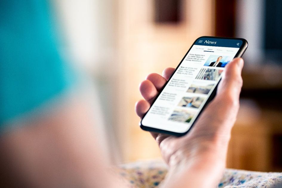 Eine Hand hält ein Smartphone, auf dem eine Nachrichten-App zu sehen ist.