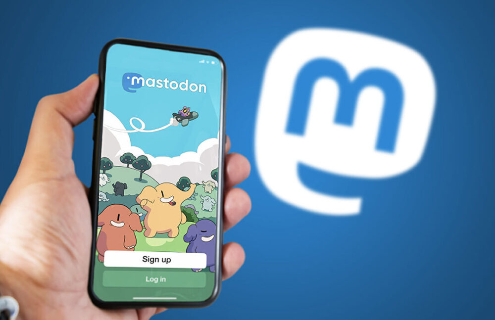 Smartphone mit geöffneter Mastodon-App vor blauem Hintergrund mit Mastodon-Logo.