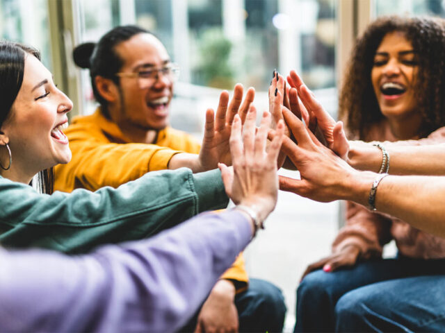 Eine Gruppe junger Leute gibt sich ein High Five.