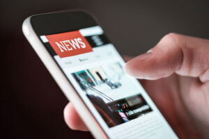 Person hält ein Smartphone in der Hand und liest Nachrichten auf einer News-Website