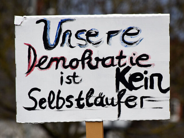 Schild auf einer Demo mit Schriftzug „Unsere Demokratie ist kein Selbstläufer“